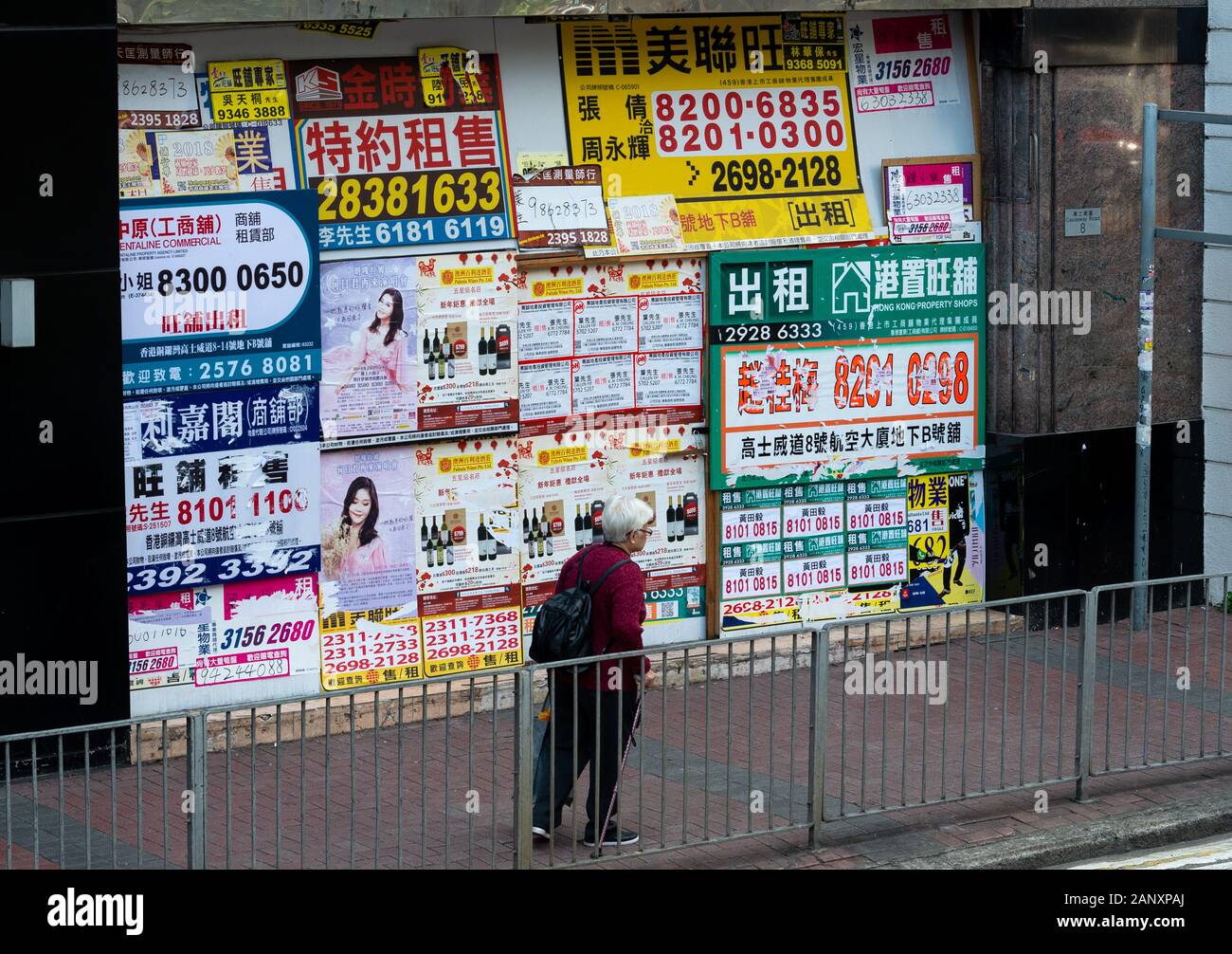 A recently closed shop front is plastered with estate agent advertisements in Wan Chai Hong Kong. Businesses in Hong Kong suffer regularly being force Stock Photo