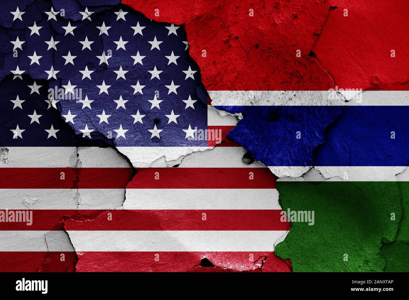 flags of USA and Gambia painted on cracked wall Stock Photo