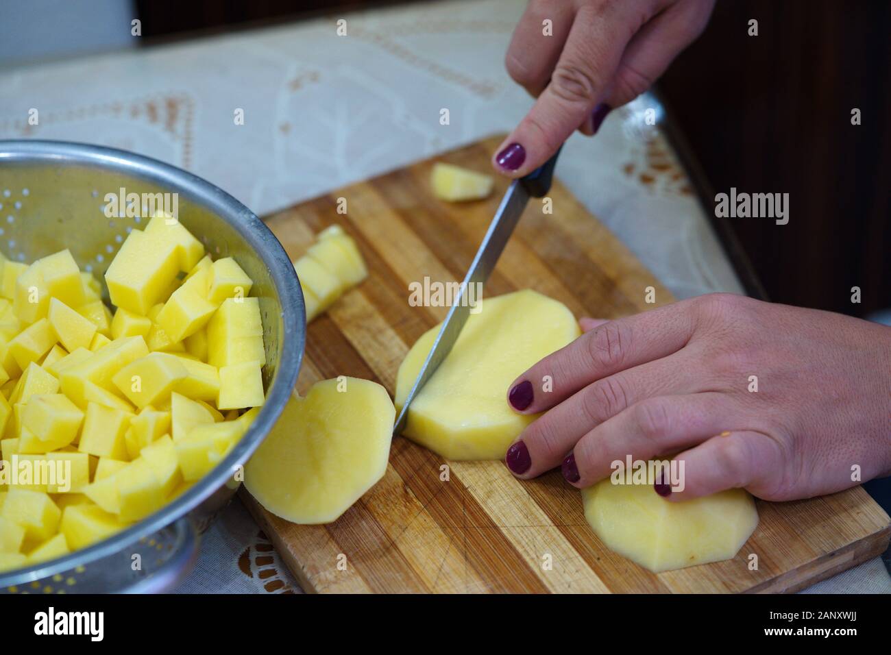 french fries preparation. woman is cutting potato in cubic shape Stock