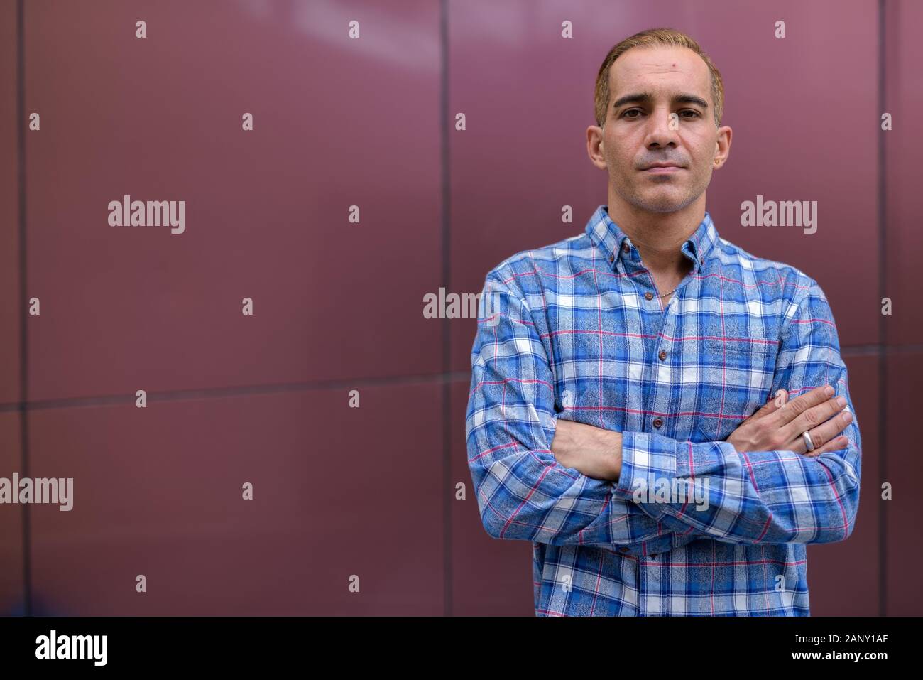 Mature Persian hipster man against glossy wall Stock Photo