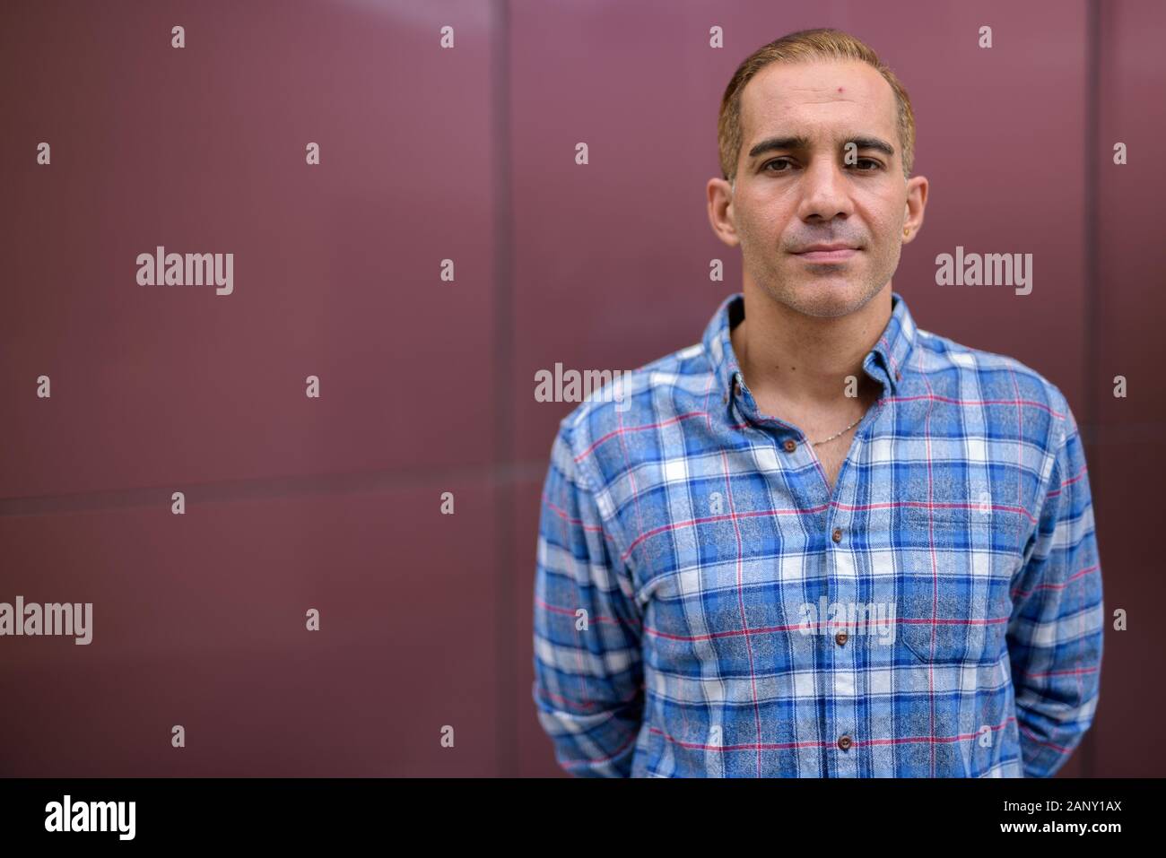 Mature Persian hipster man against glossy wall Stock Photo