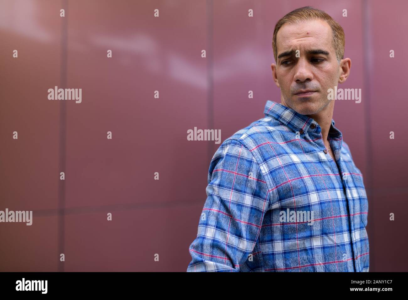 Mature Persian hipster man against glossy wall Stock Photo