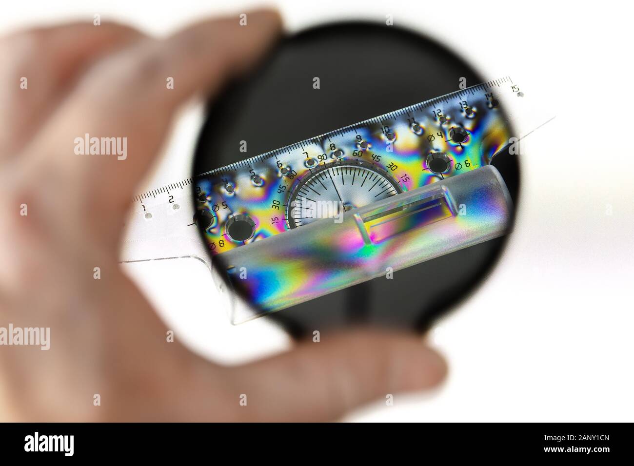 Transparent plastic protractor with ruler, photographed through a polarizing filter with a polarized light source. Stock Photo