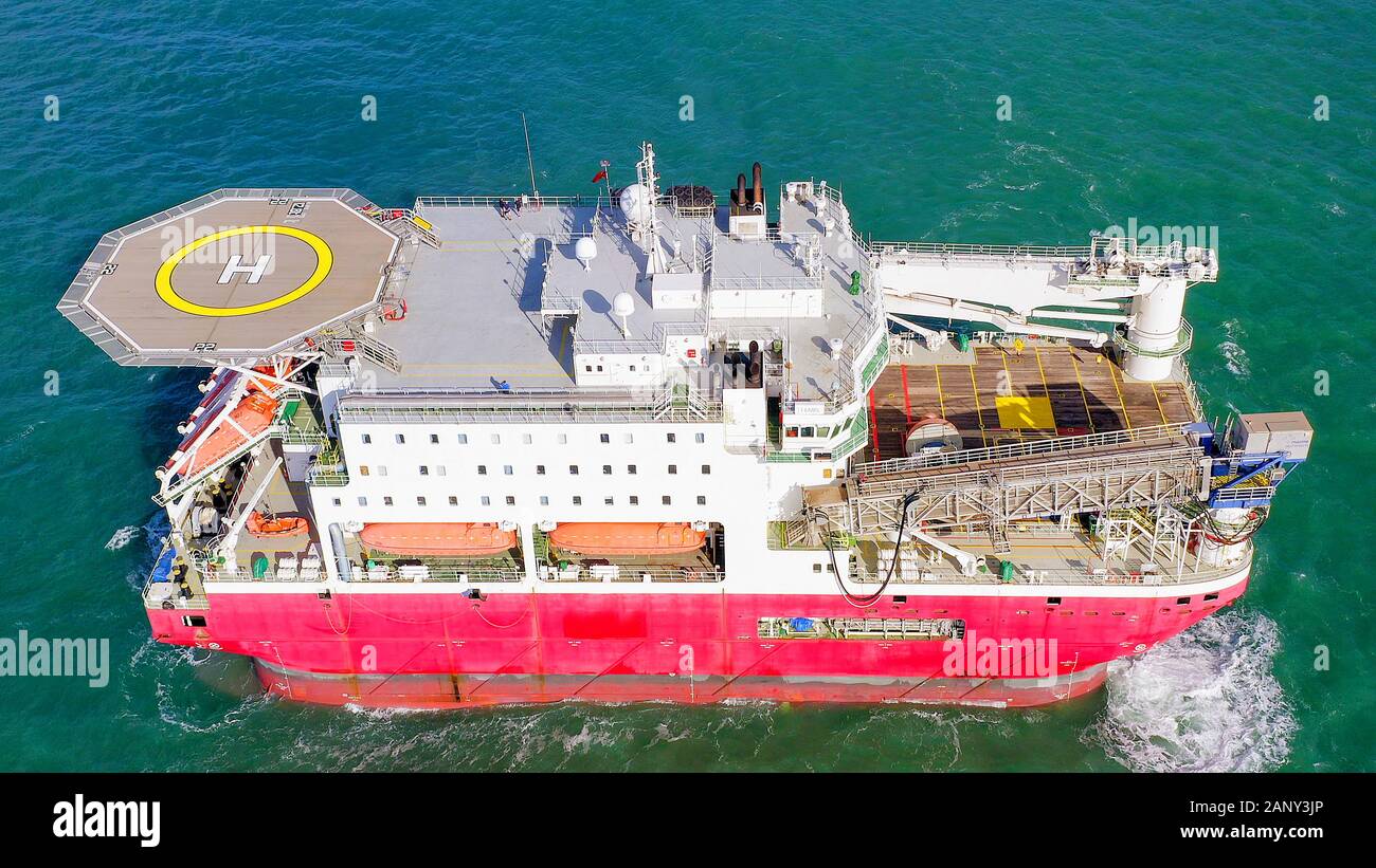 Large Platform supply ship with Helipad and two large cranes, anchored at Sea, Aerial view. Stock Photo