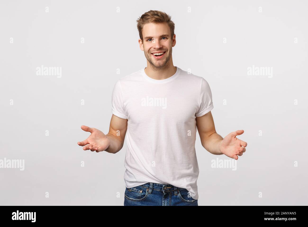 Man extending hands forward to hold something, leaning to product, helping out friend carry heavy boxes, smiling joyfully, friendly looking forward Stock Photo