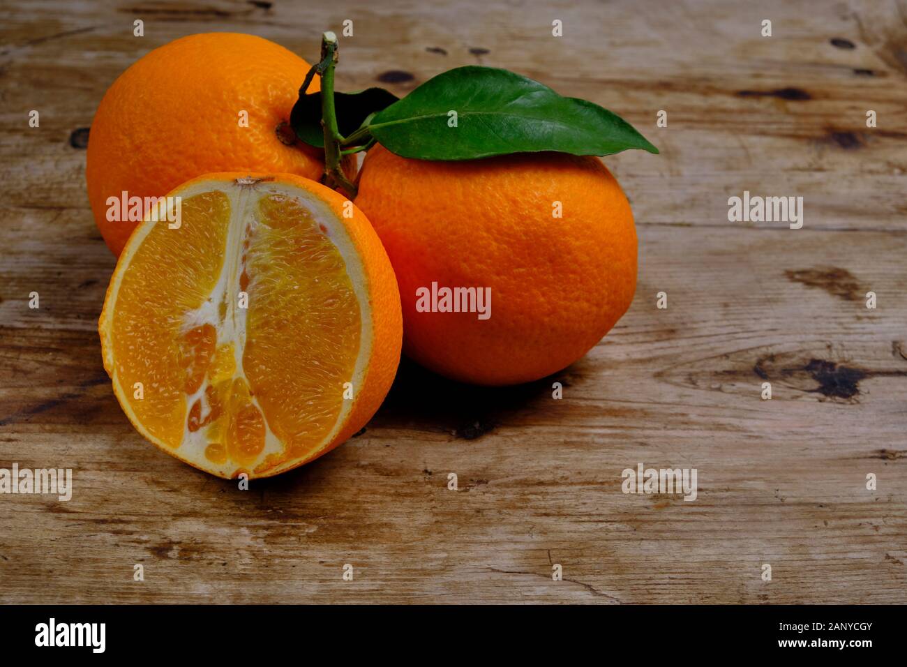 Oranges with leaves on the weathered wooden surface. Stock Photo
