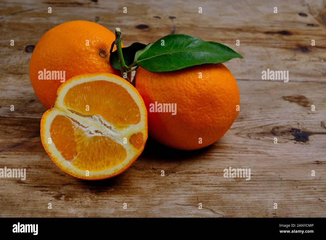 Oranges with leaves on the weathered wooden surface. Stock Photo