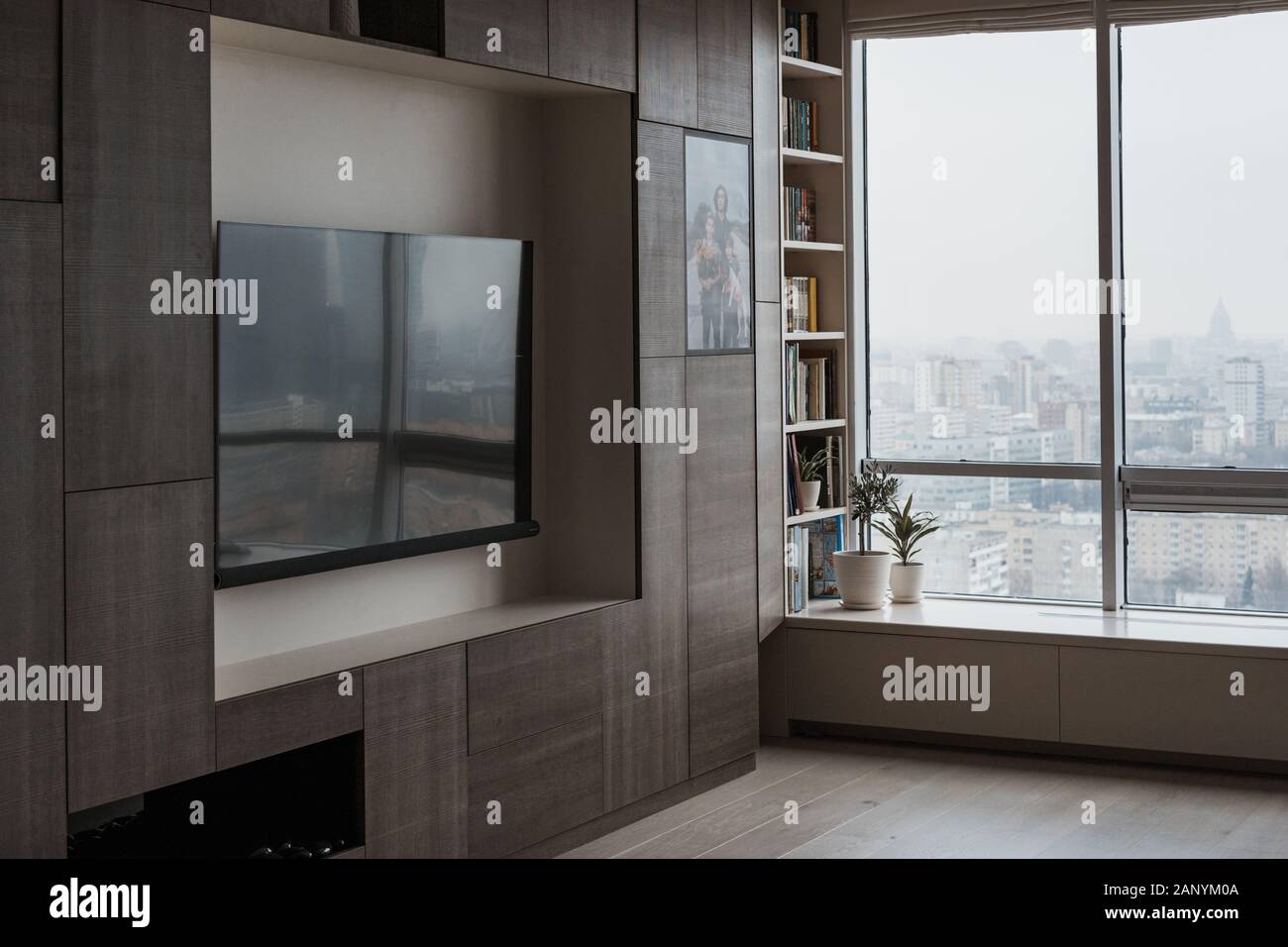 Furniture in a modern style, a large TV screen in the modern living room with panoramic windows. Comfortable living space. Stock Photo