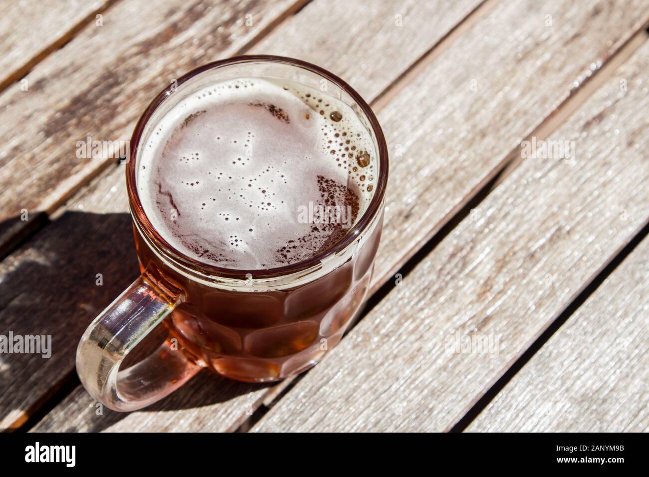 Glass cup of cold beer on a wooden surface on a hot sunny day Stock Photo