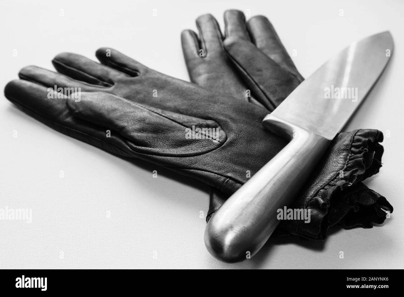 Selective focus shot of metal knife over black gloves on a white surface Stock Photo