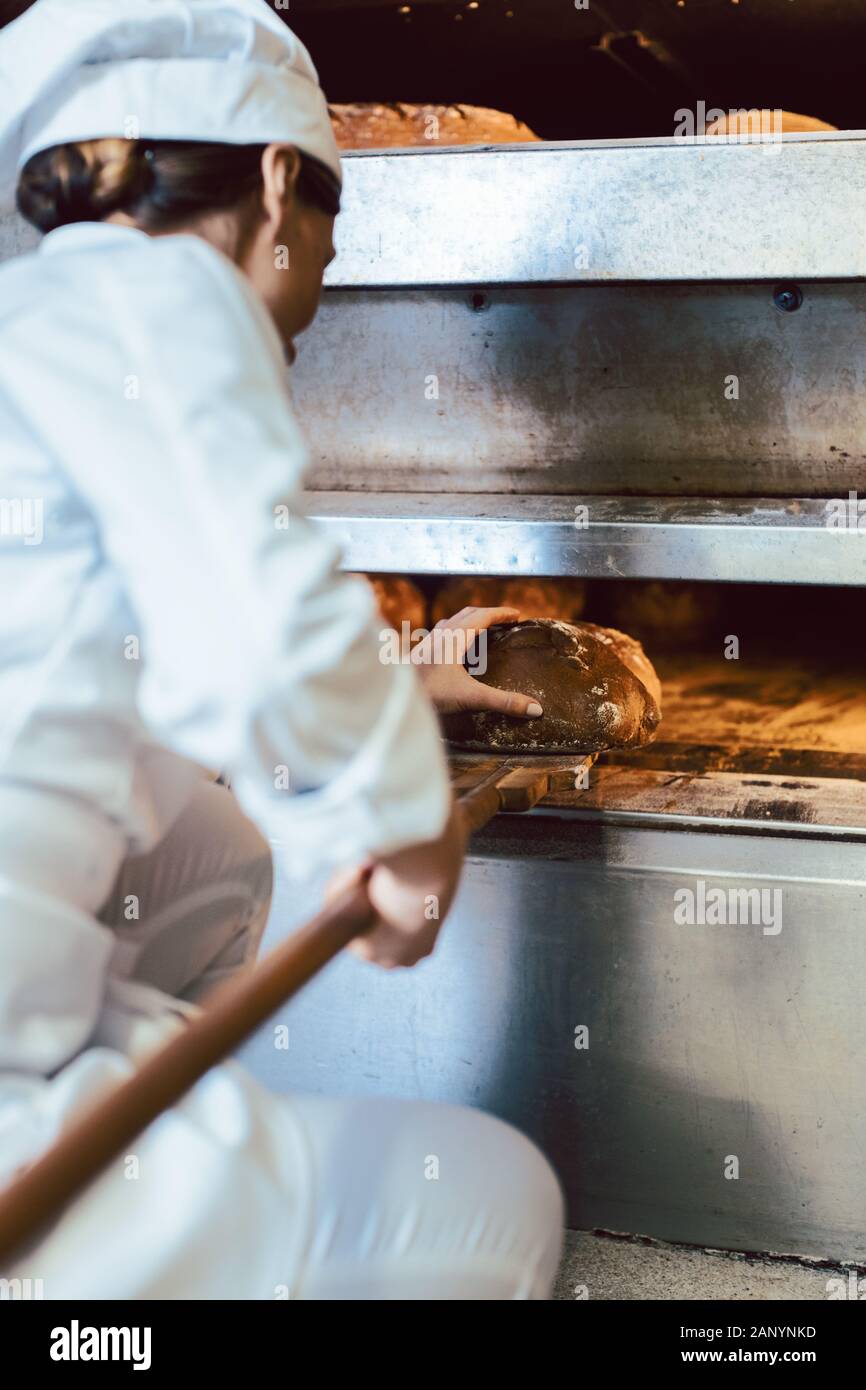 Baker putting bread in the bakery oven Stock Photo Alamy