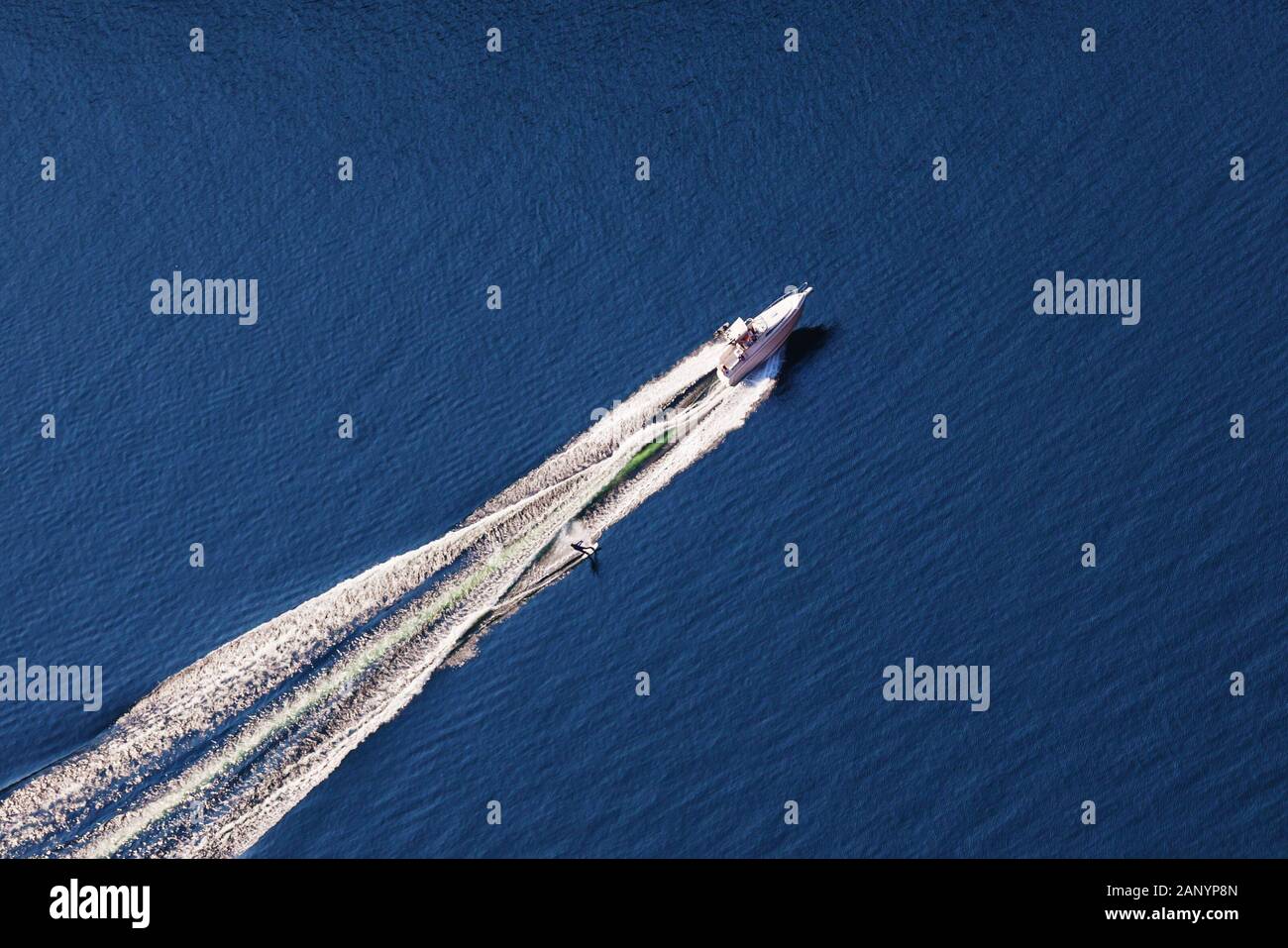 Aerial view of man wakeboarding on lake. Water skiing on lake behind a boat. Stock Photo