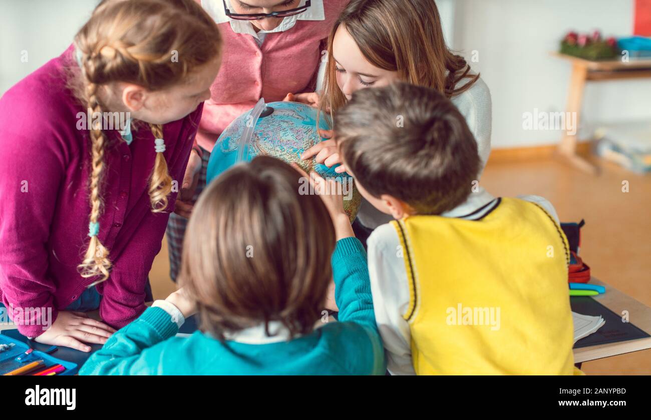 Pupils and teacher in geography class studying a globe Stock Photo