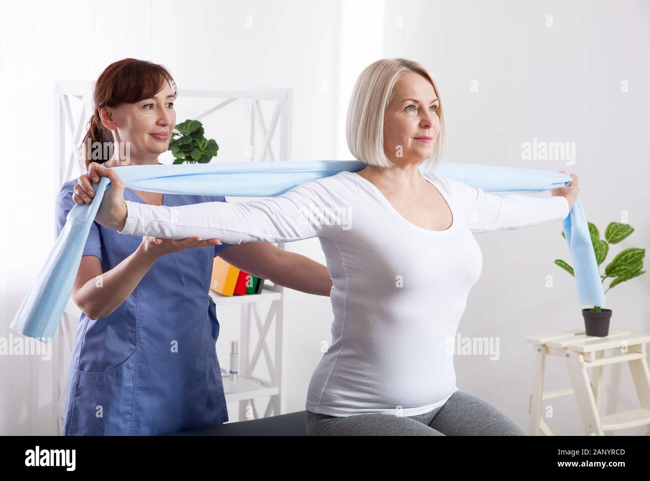 Physiotherapy, sport injury rehabilitation treatment with Resistance Band. Woman having chiropractic back adjustment. Osteopathy, Alternative medicine, pain relief concept. Front view. Stock Photo