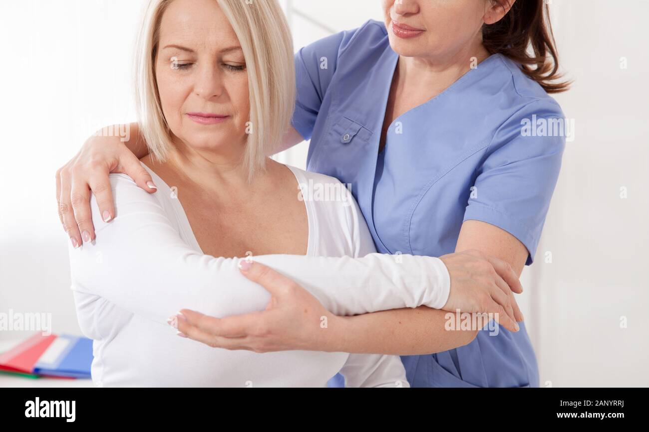 Physiotherapist working with middle aged woman patient in clinic Stock Photo