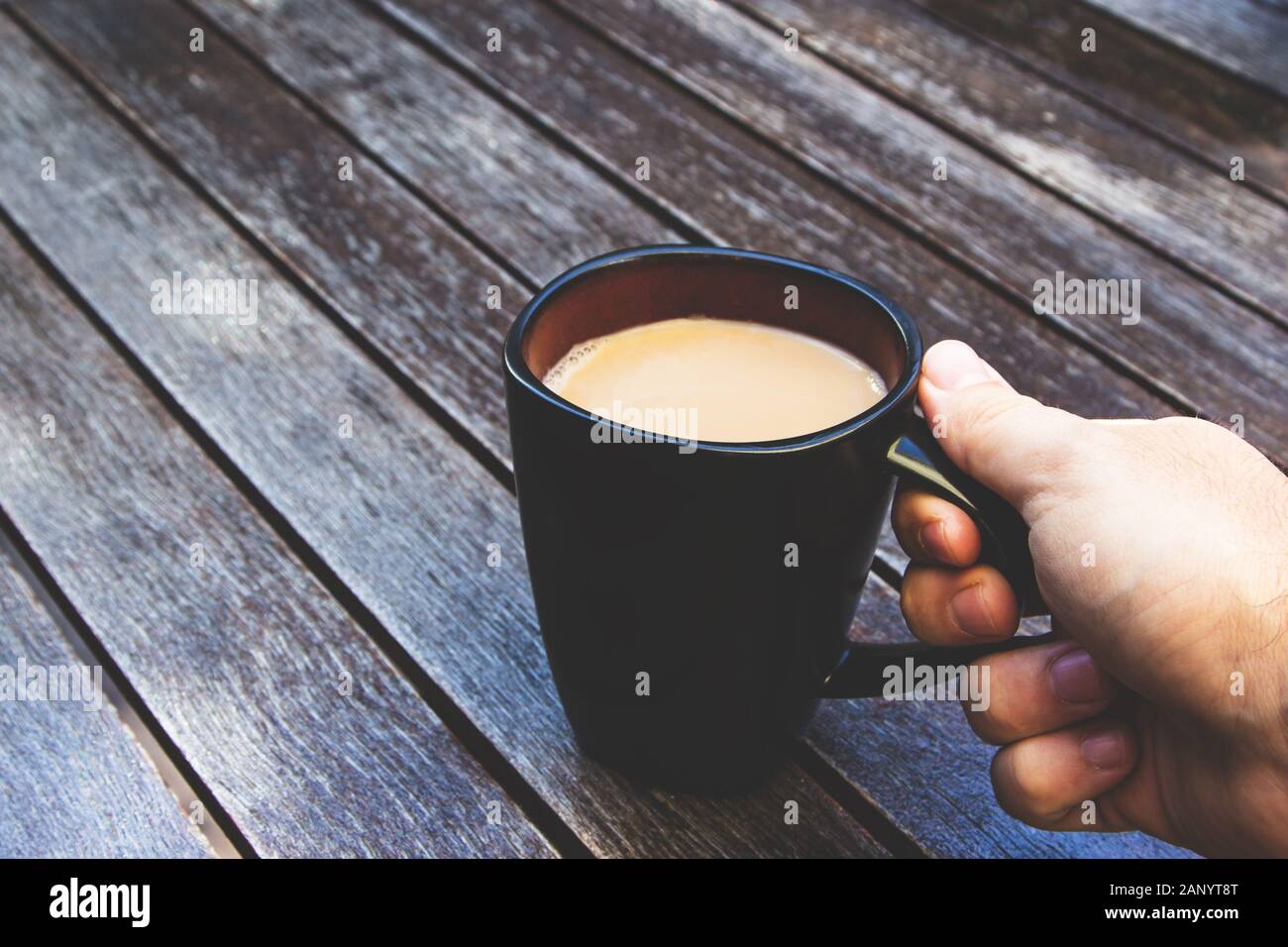 Person holding its black mug filled with coffee on a wooden surface Stock Photo - Alamy Person holding its black mug filled with coffee on a wooden surface Stock Photo - Alamy