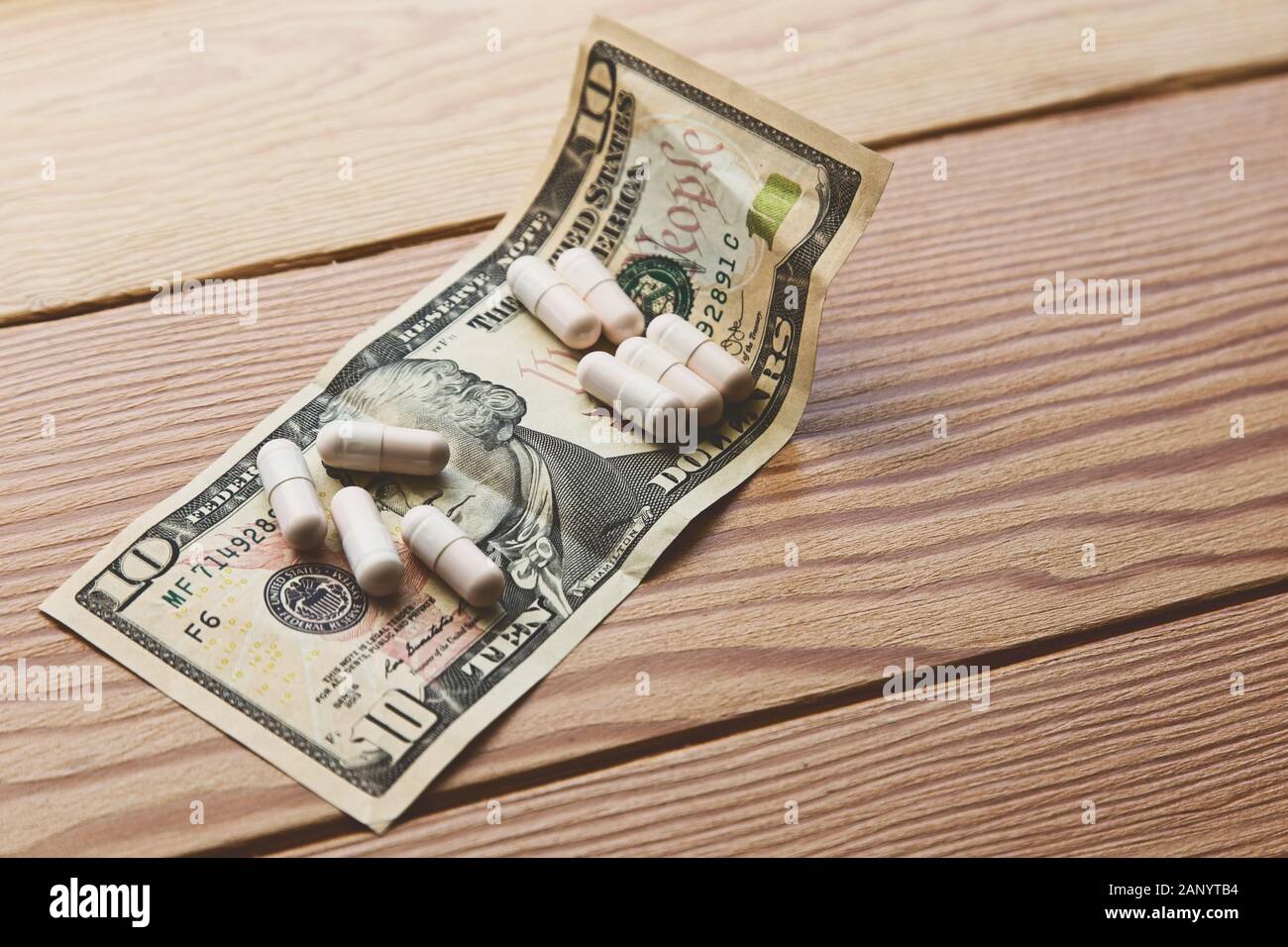 High angle shot of some capsules on a US 10 dollar on a wooden table Stock Photo