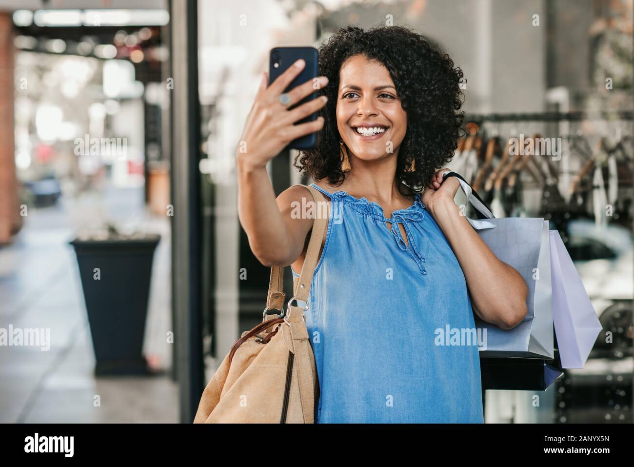 Smiling young woman taking a selfie while out clothes shopping Stock Photo