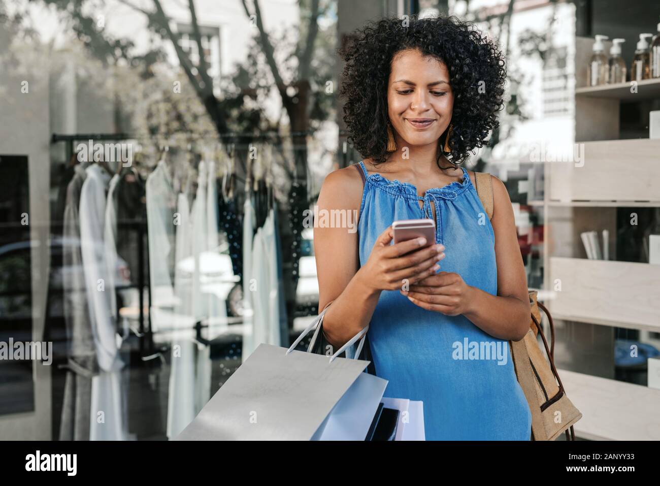 Smiling young woman reading a text message while out shopping Stock Photo