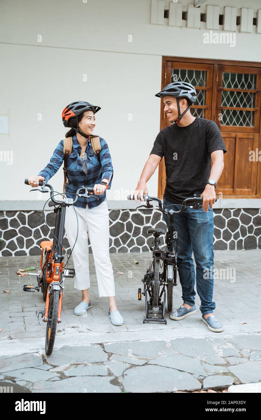 young couples prepare folding bikes and wear helmets before going out Stock Photo