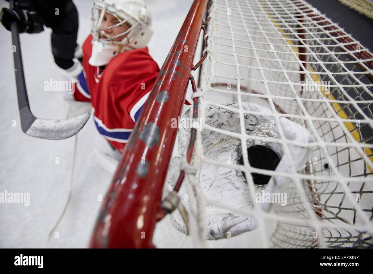 Action shot of female team playing hockey, focus on goalkeeper catching pluck in gate, copy space Stock Photo