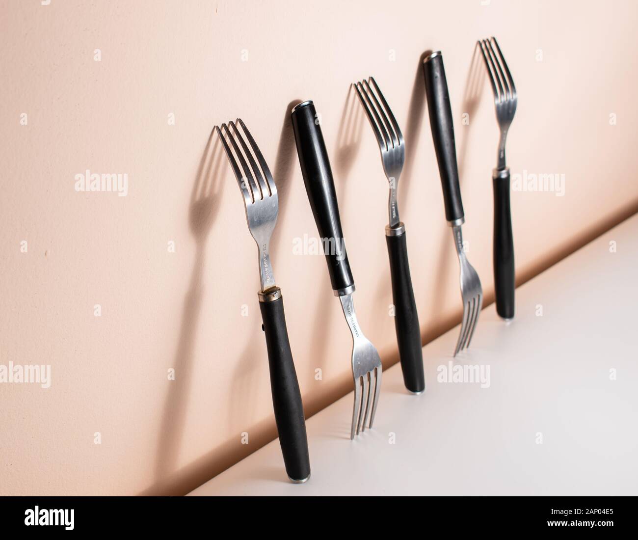 Forks standing on a wall, with big shadows between them. Silverware and their shadows on the wall Stock Photo