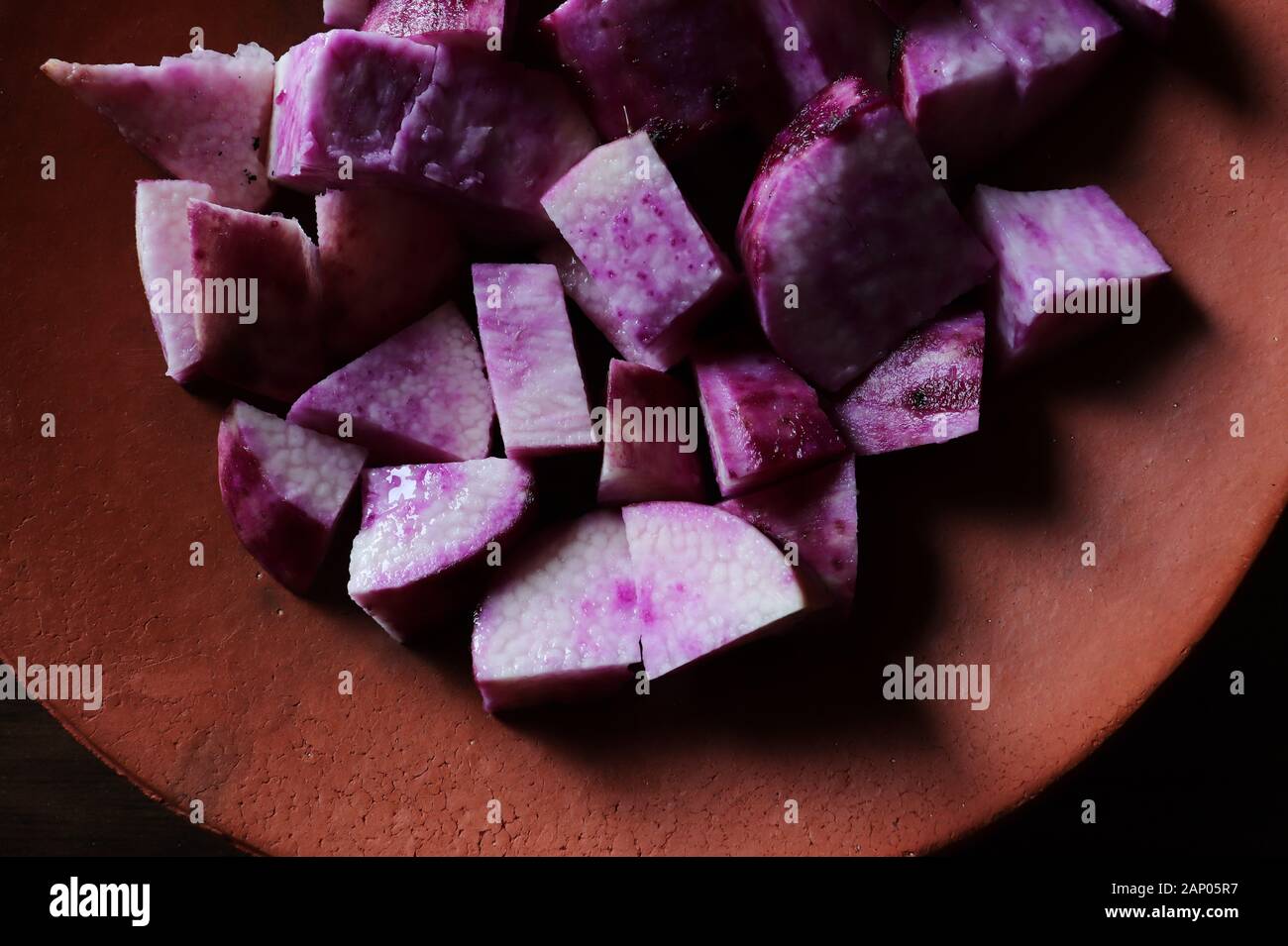Close-up of chopped purple yam/Dioscorea alata in a terracotta plate Stock Photo
