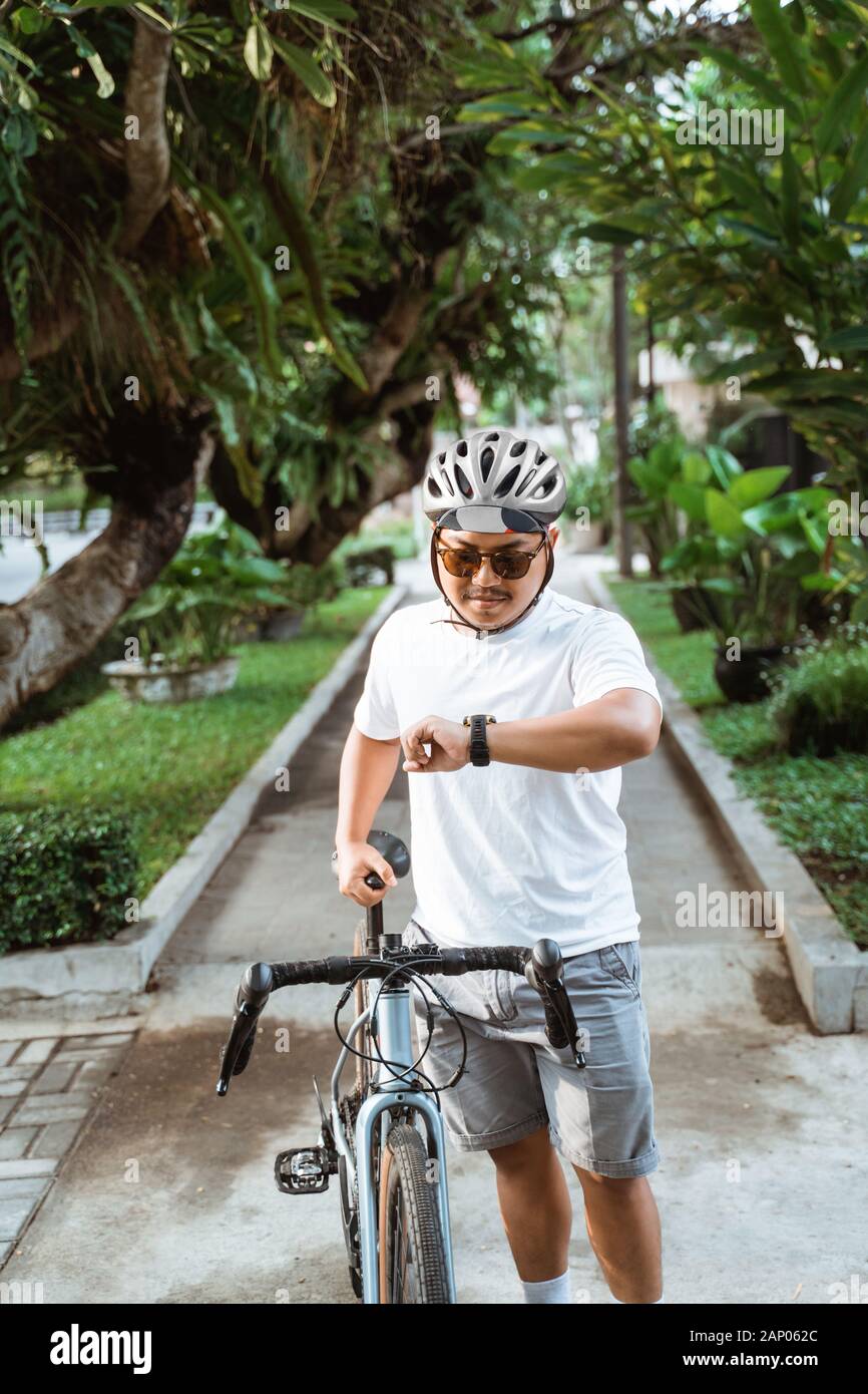 asian young man wearing helmet walk with road bike when looking