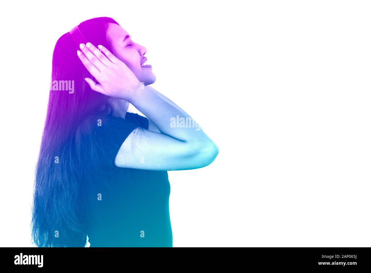 Side view of diverse Asian millennial girl listening to music on headphones with retro duotone gradient filter - Hispanic lifestyle woman, enjoying audio technology isolated on white background Stock Photo