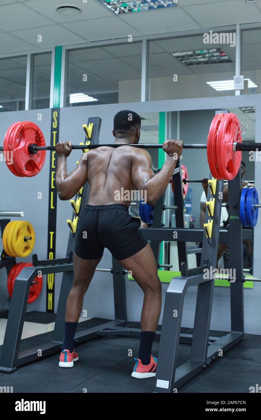 Fit young man in sportswear straining to lift heavy weights during a  workout session in a gym. Back view. Black african male focused on his  exercise Stock Photo - Alamy