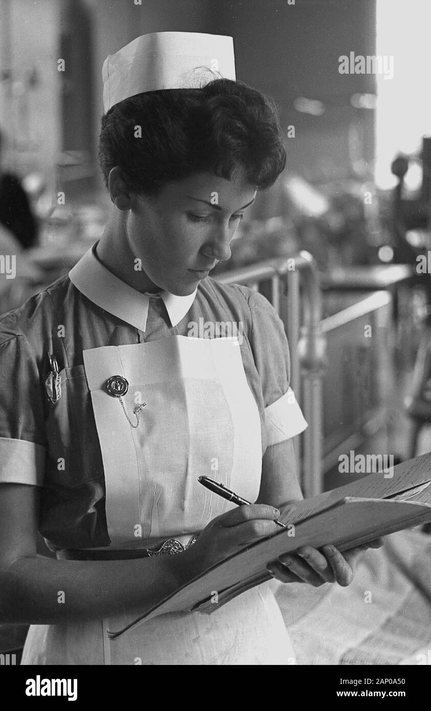 1950s, historical, a nurse on a hospital ward writing up a patient's medical notes, England, UK. Stock Photo