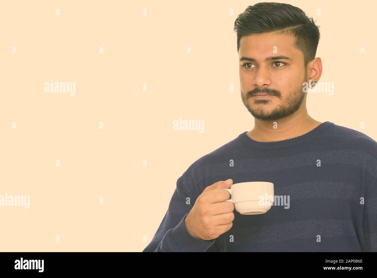 Young handsome Indian man holding coffee cup Stock Photo