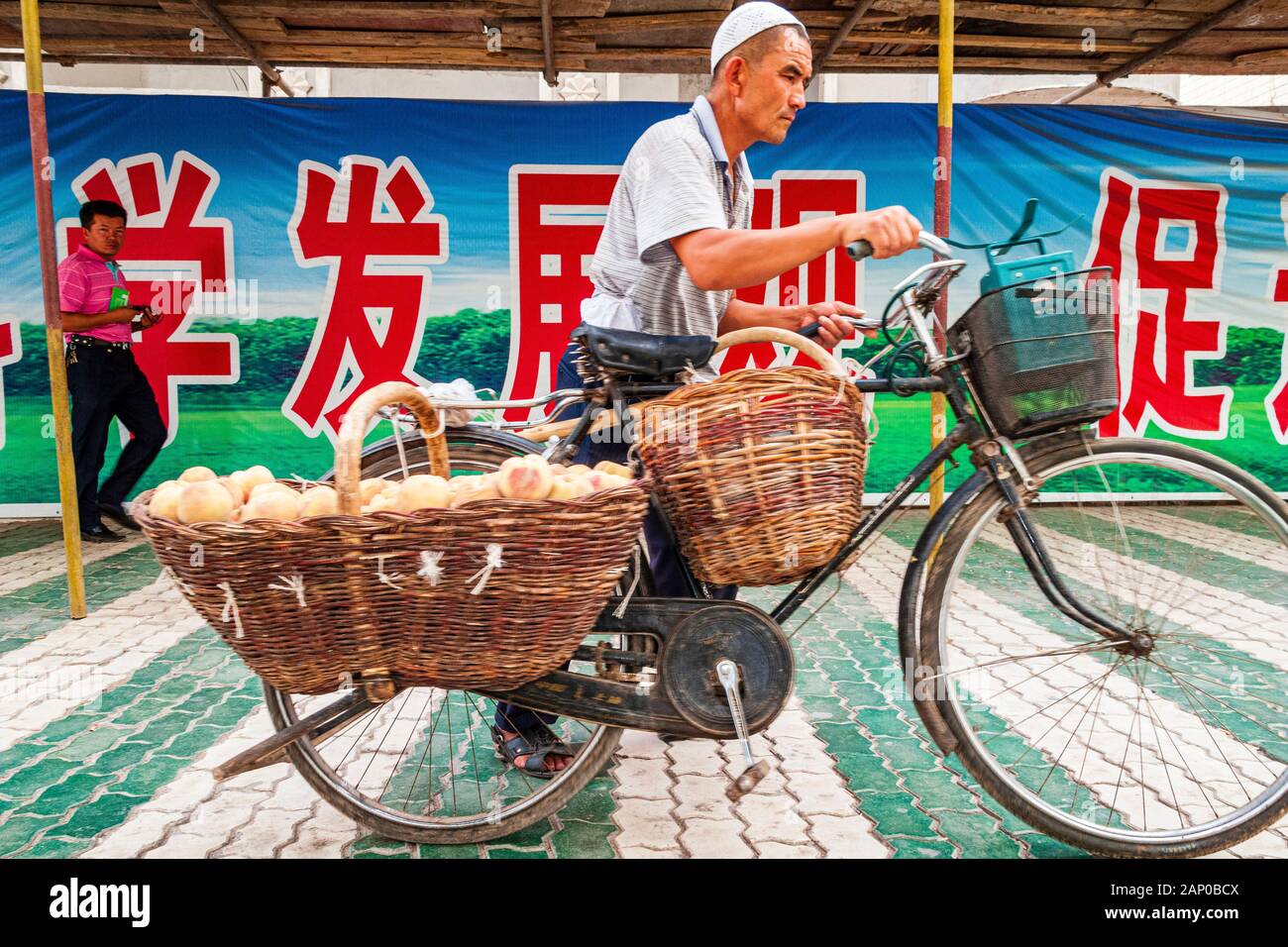 Uigur man is transporting eggs on a bicycle in the streets of the destroyed old part of the Oasis Stock Photo