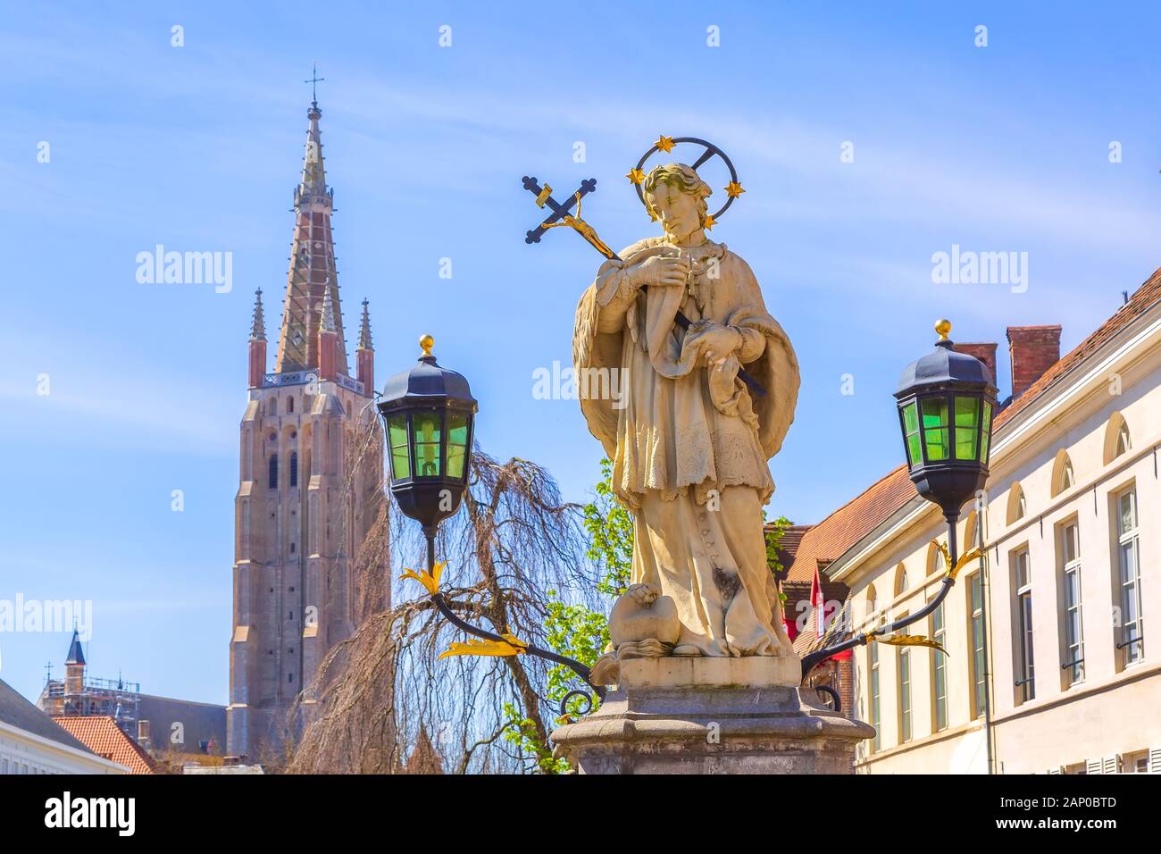 Bruges, Belgium statue of Johannes Nepomucenus, church tower in Brugge Stock Photo