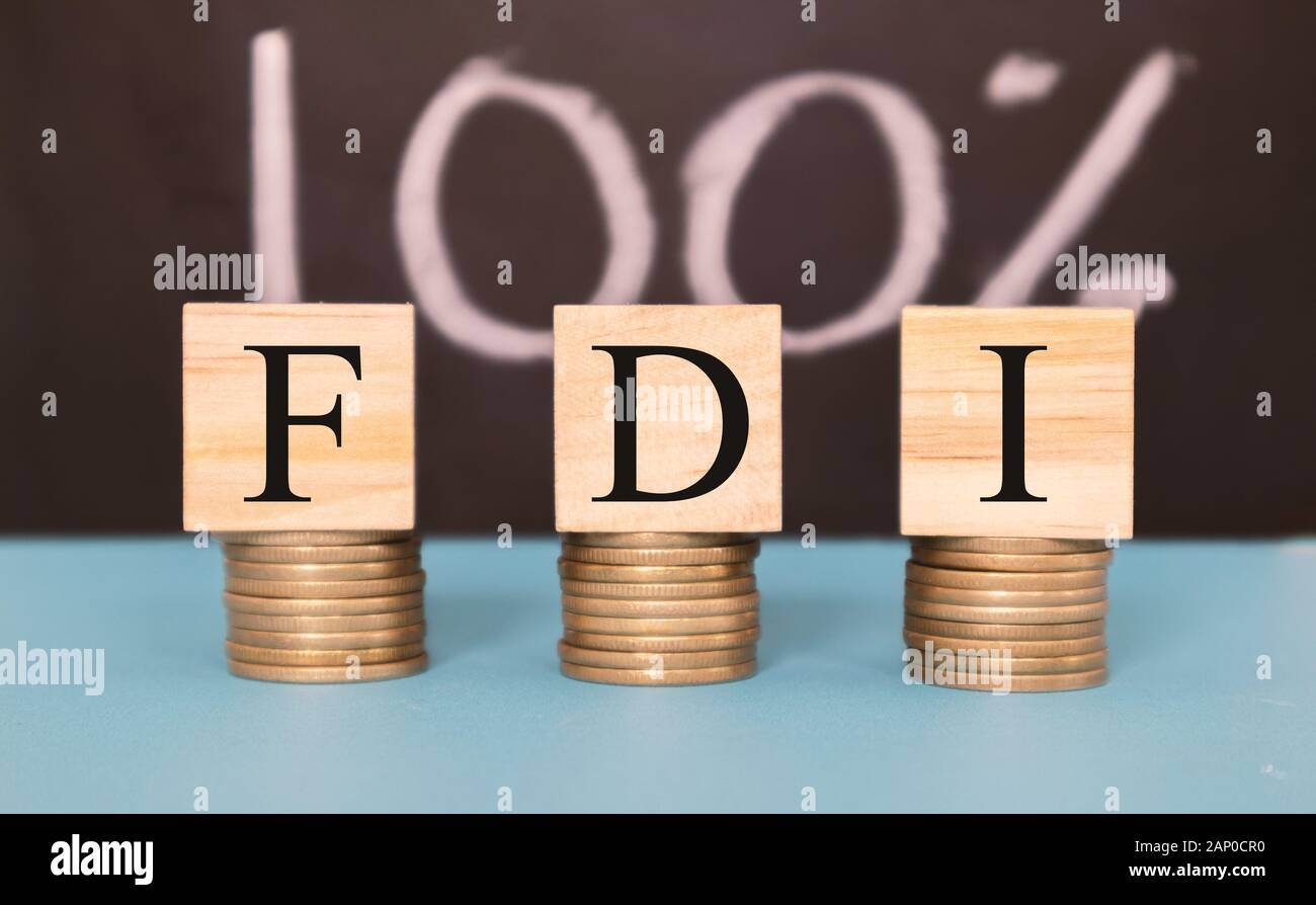 Finance Concept with Stack of Coins - 100 percent FDI or Foreign Direct Investment on wooden blocks. Stock Photo