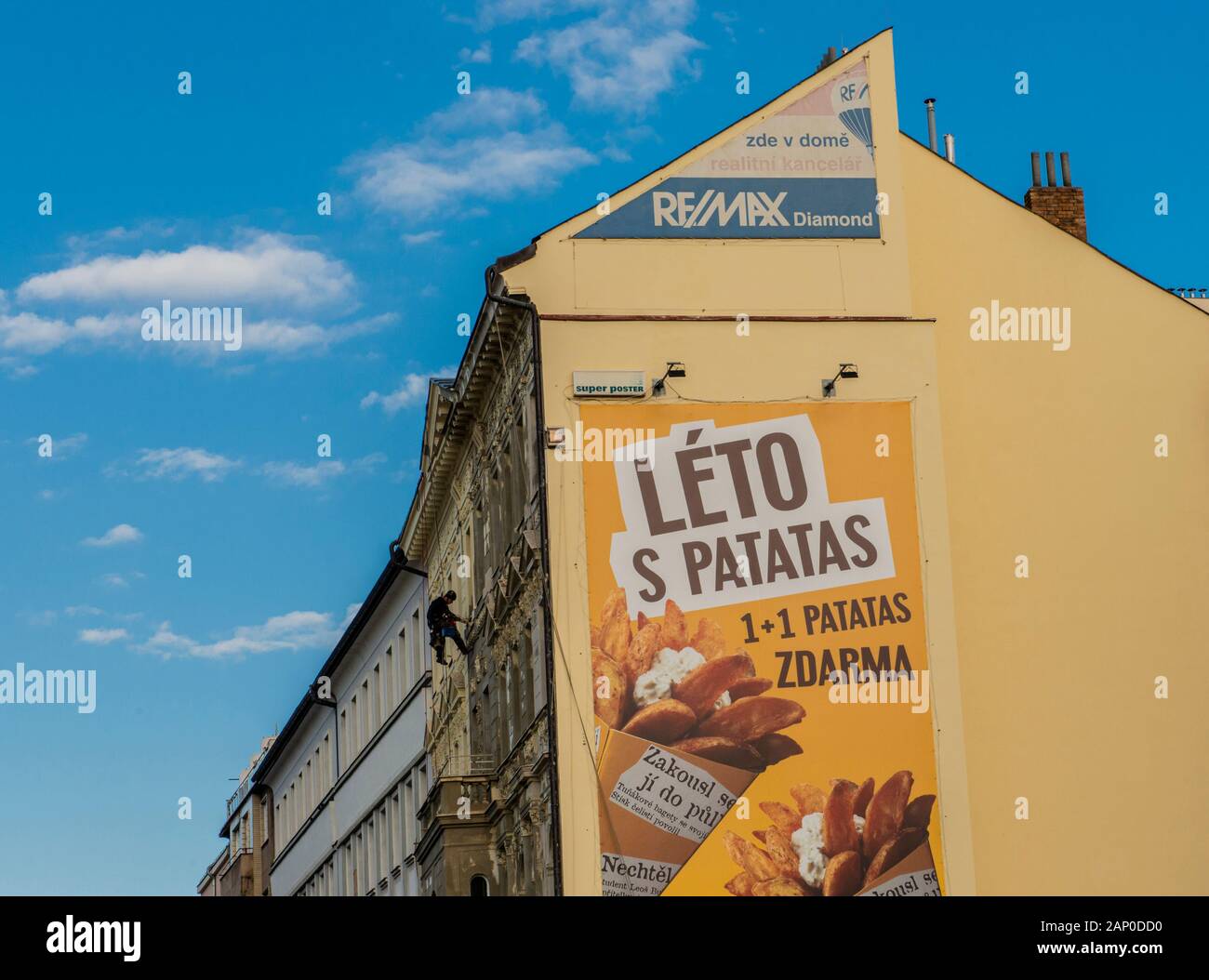 Large billboard on wall of yellow building with man abseiling in Prague in the Czech Republic. Stock Photo