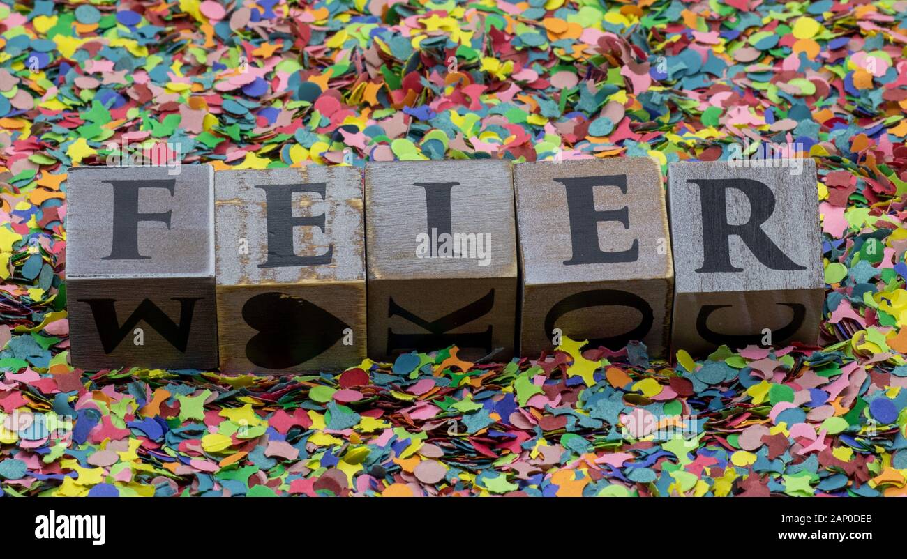 "Feier" written on wooden blocks isolated on confetti background Stock Photo
