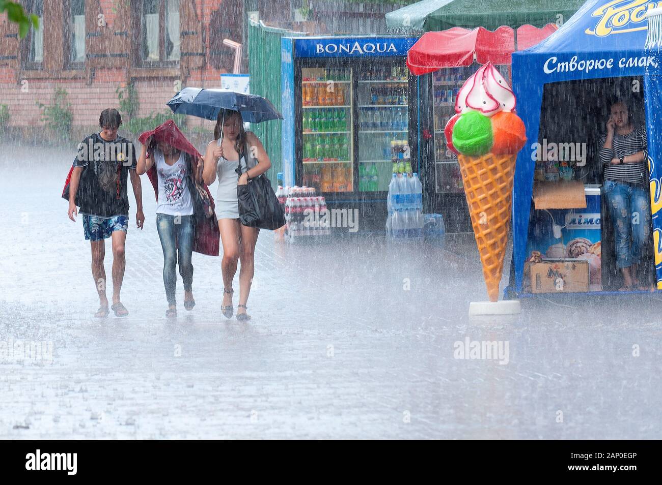 Three young people get caught in heavy rain in Kiev. Stock Photo
