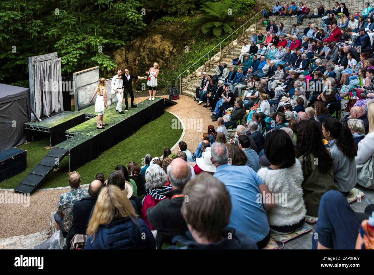 Audience watching actors performing A Misummer Night's Dream at Trebah Garden Amphitheatre in Cornwall. Stock Photo