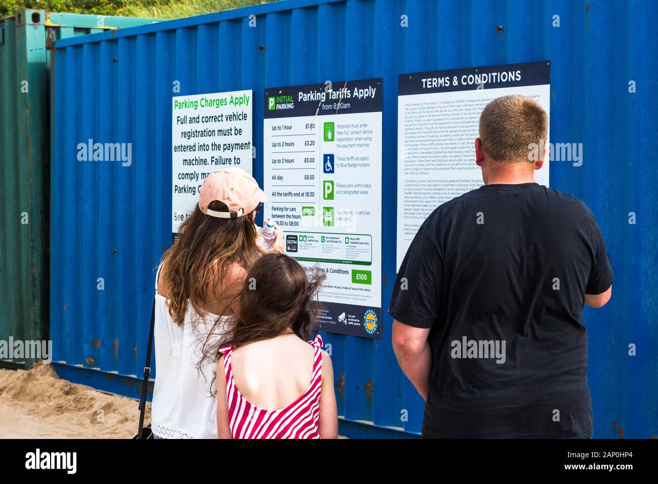 A family of holidaymakers looking at the parking charges at Fistral Car
