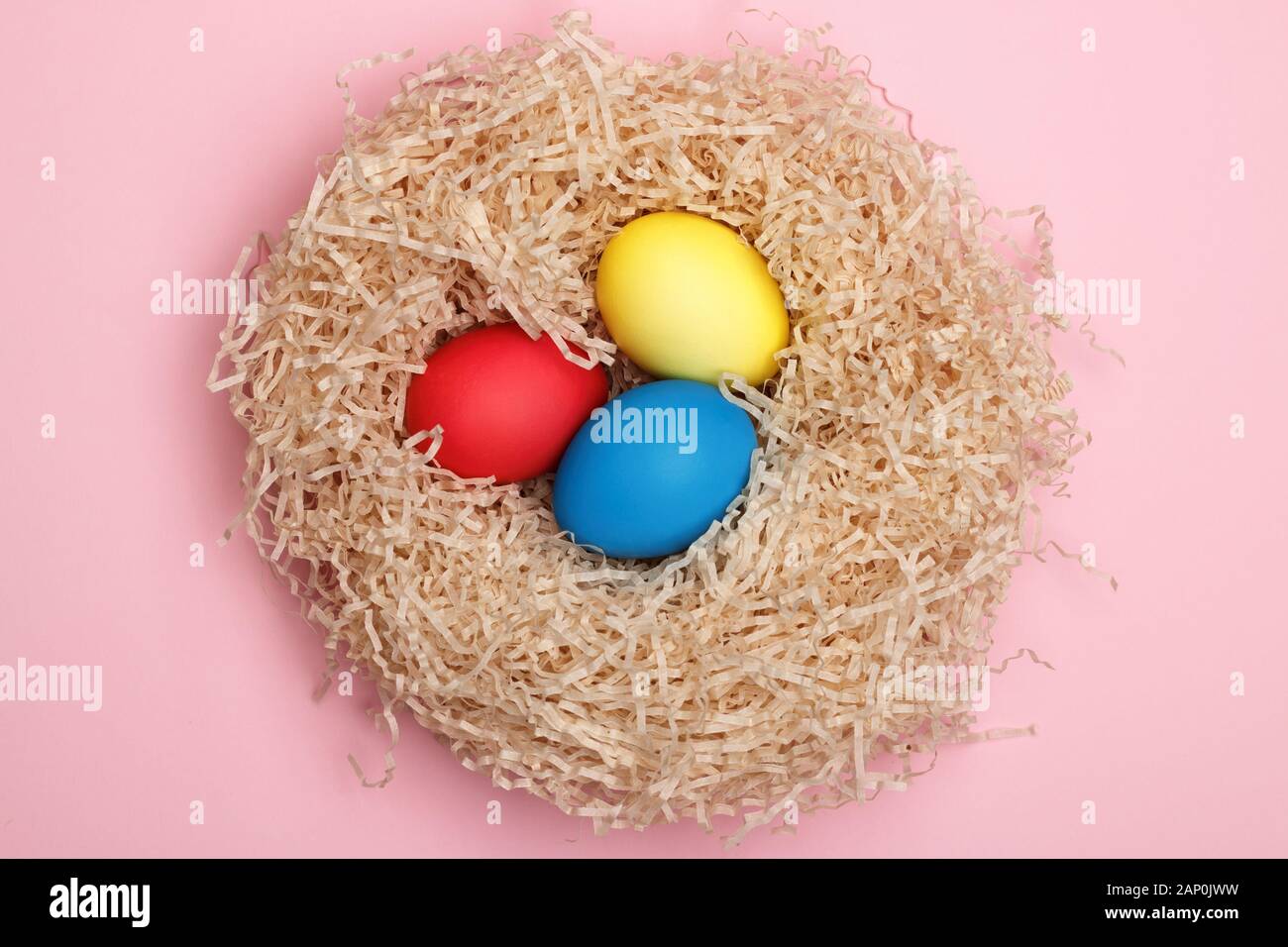 Nest with three easter eggs on a pink background. Close-up. Top view. Stock Photo