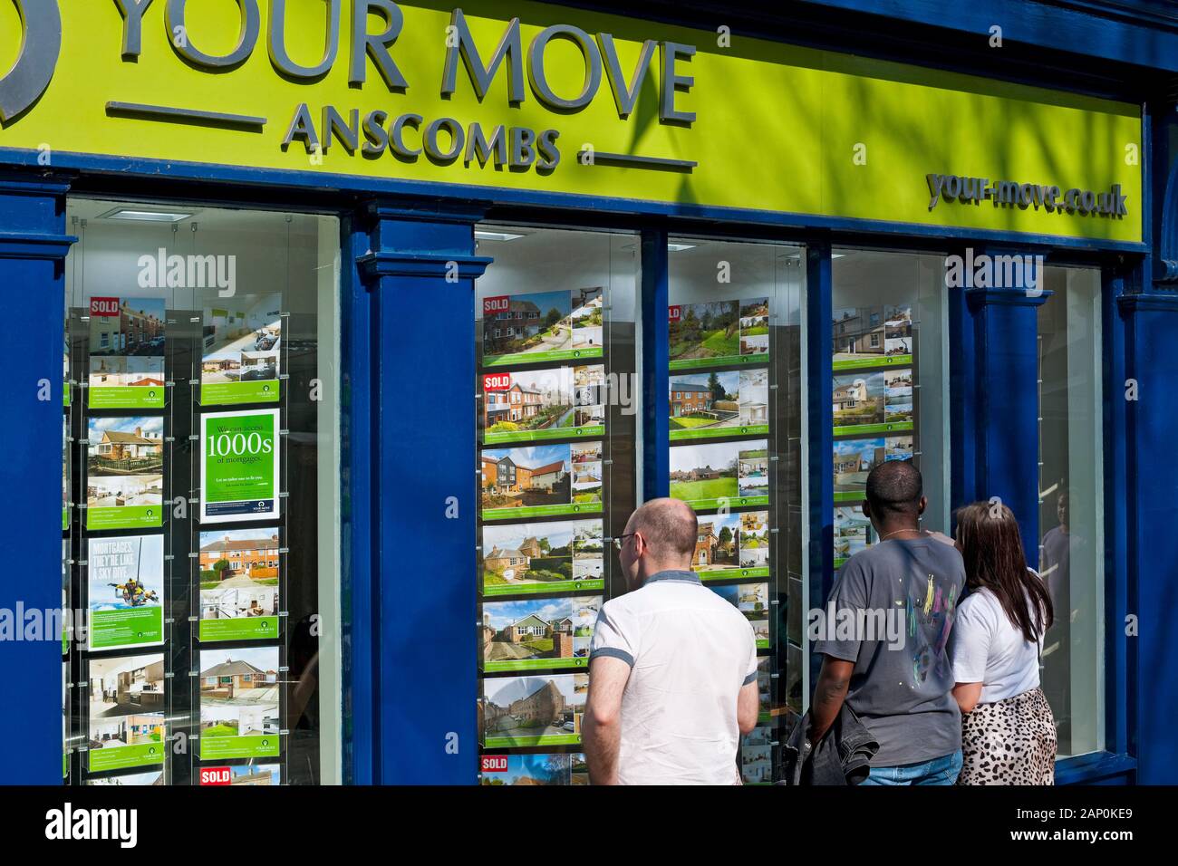 People looking at houses for sale or rent in an estate agents window. Stock Photo