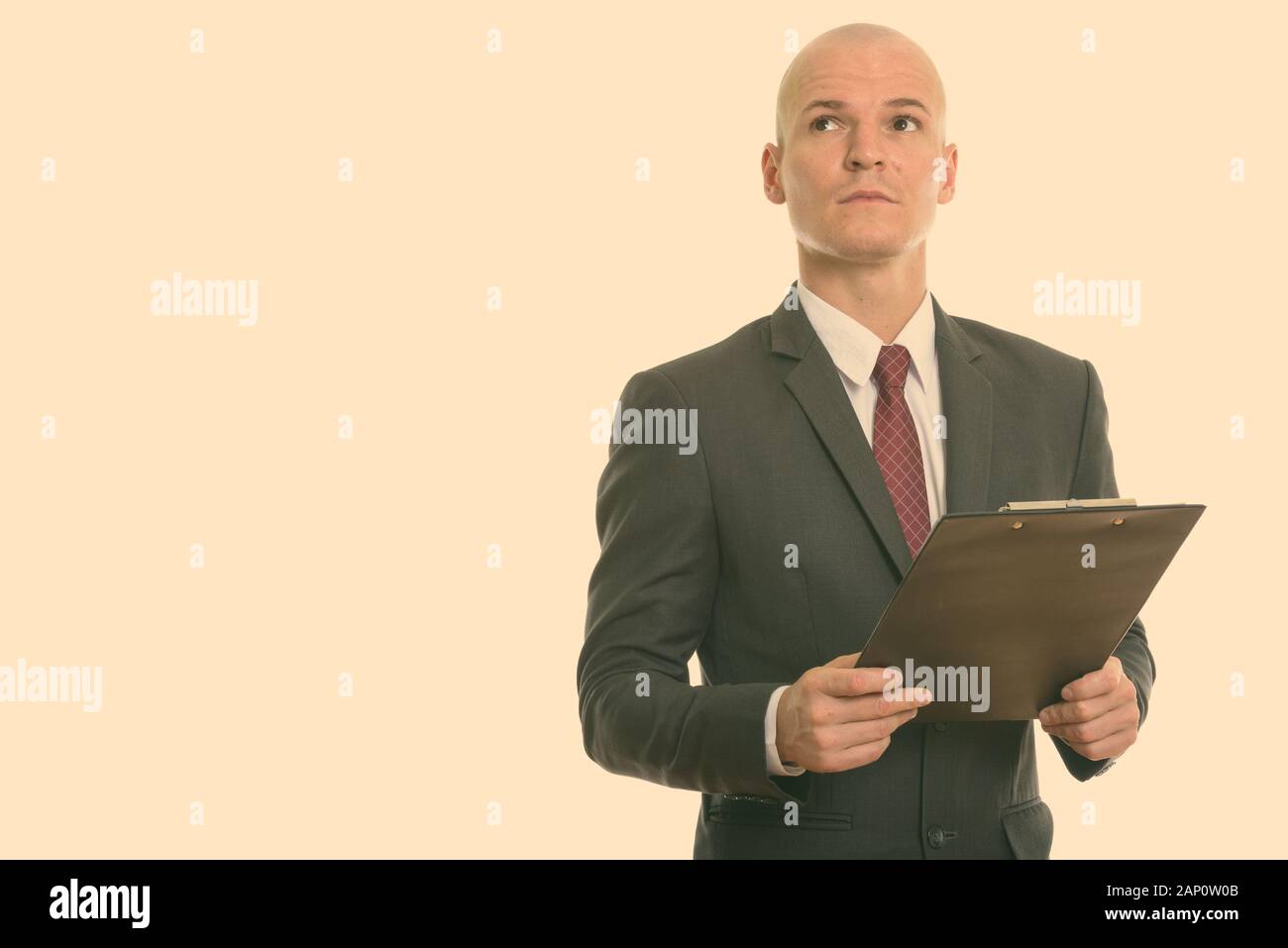 Studio shot of young handsome bald businessman in suit isolated against ...