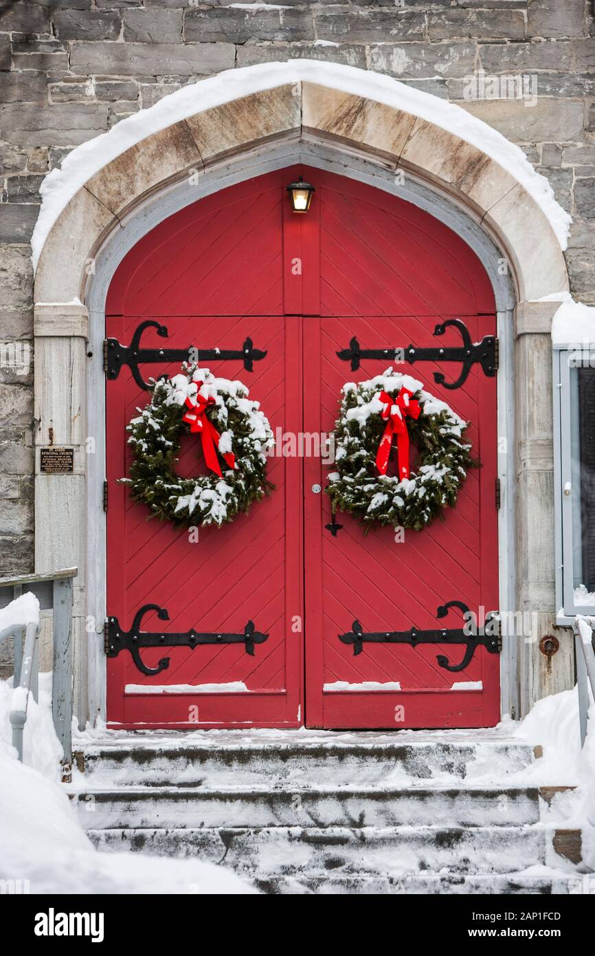 Red church doors decorated using Christmas wreaths with red bows Stock Photo