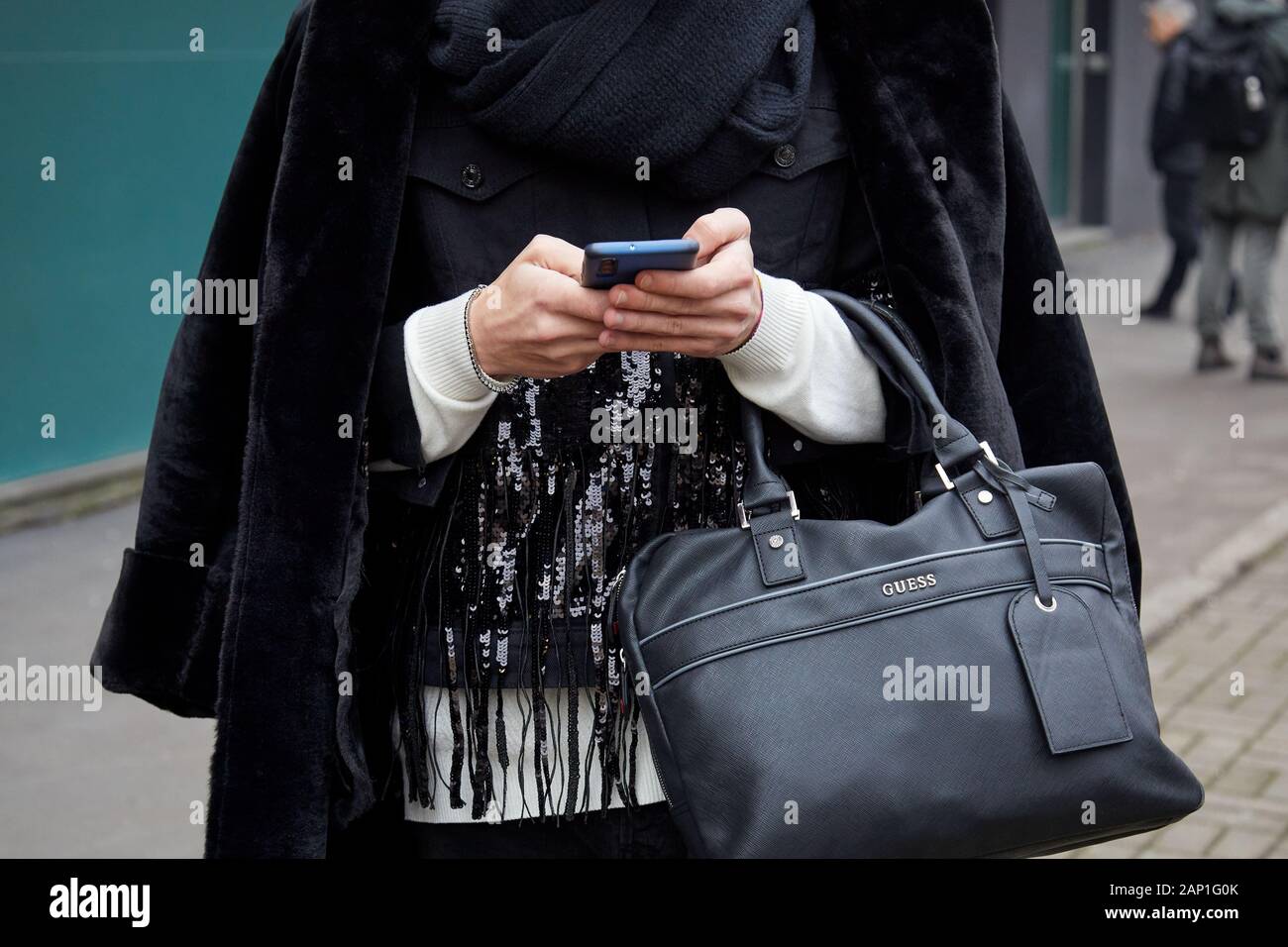 MILAN, ITALY - JANUARY 14, 2019: Man with black leather Guess bag looking  at smartphone before Marco de Vincenzo fashion show, Milan Fashion Week  stre Stock Photo - Alamy