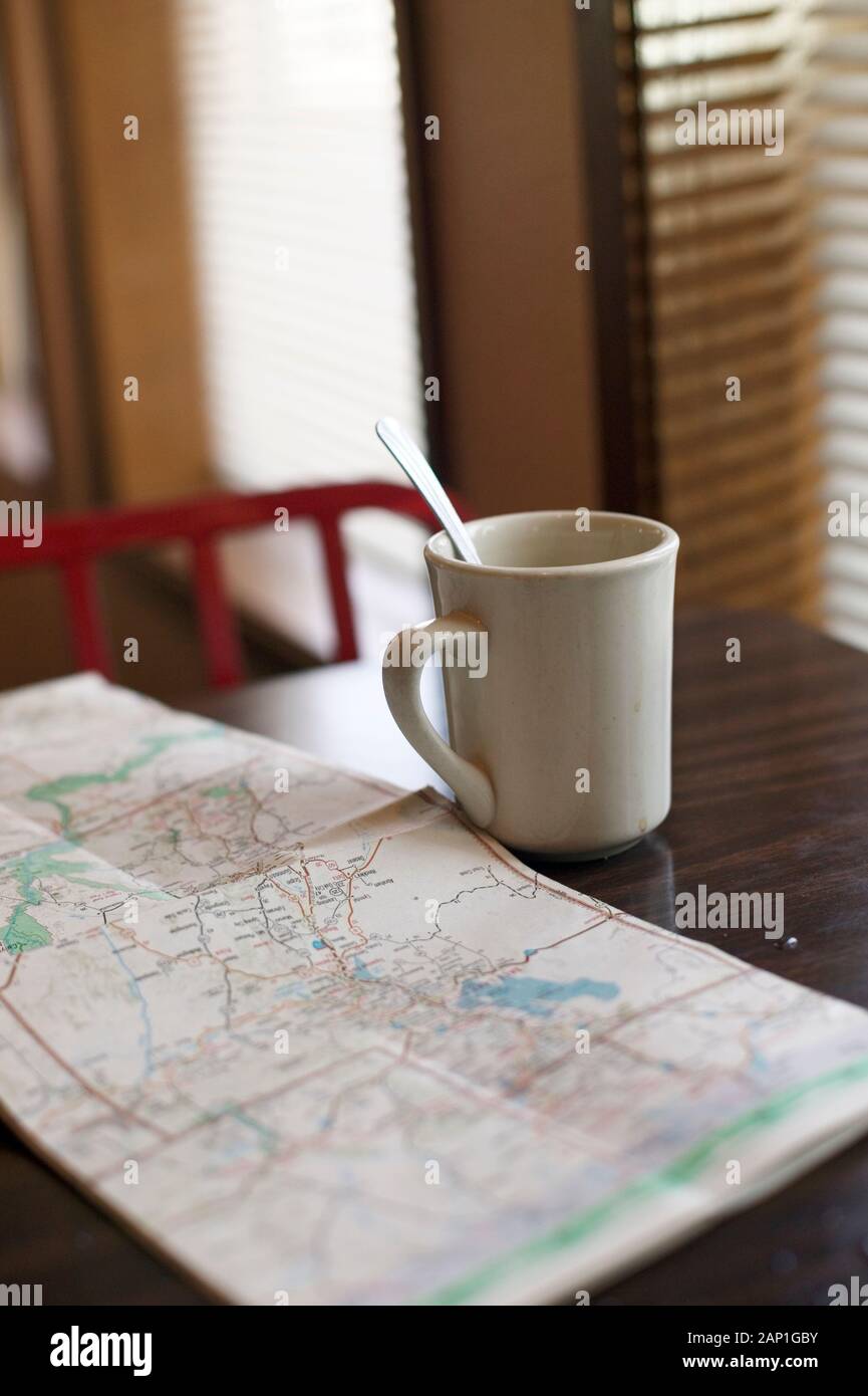 Going on a road trip. Table setting with coffee mug and roadmap at a diner Stock Photo