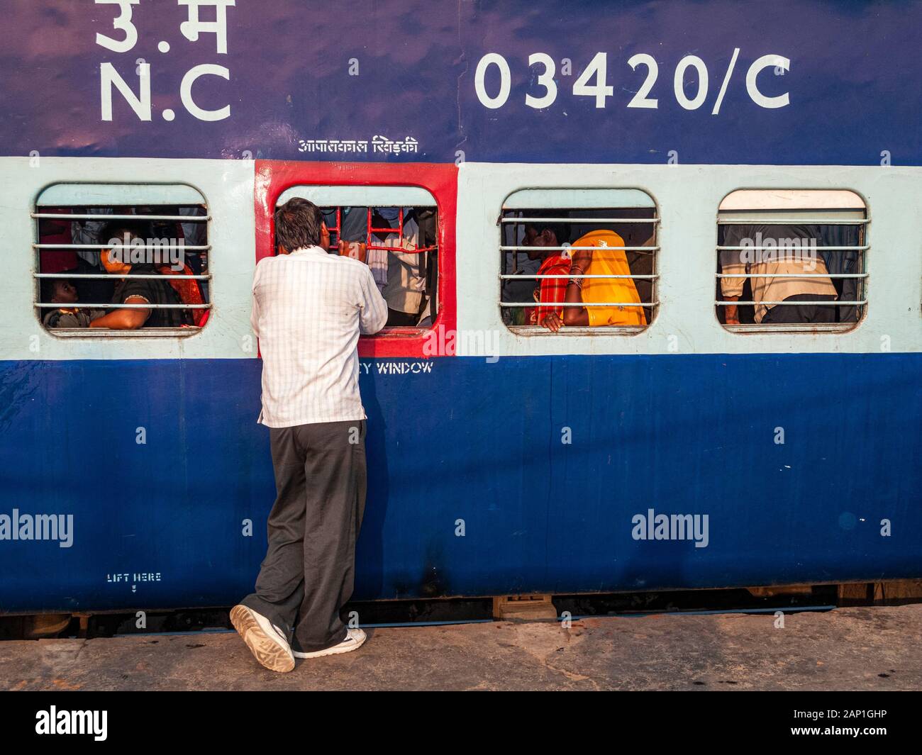 A man talking to people inside the train before leaving the New Delhi Railway Station Stock Photo