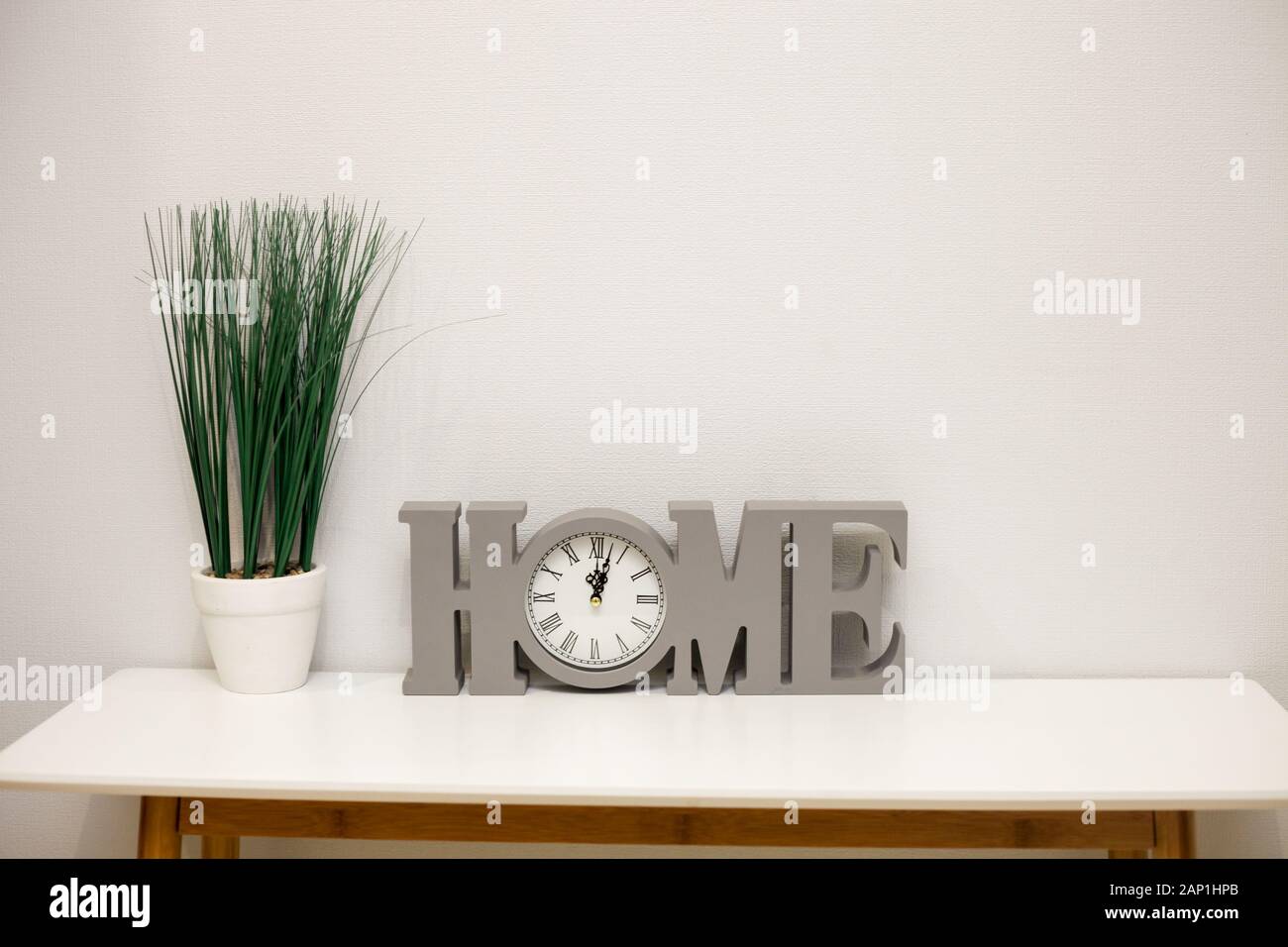 Interior decoration, flower pot and clock, home details, on wooden table against white wall, copy space Stock Photo