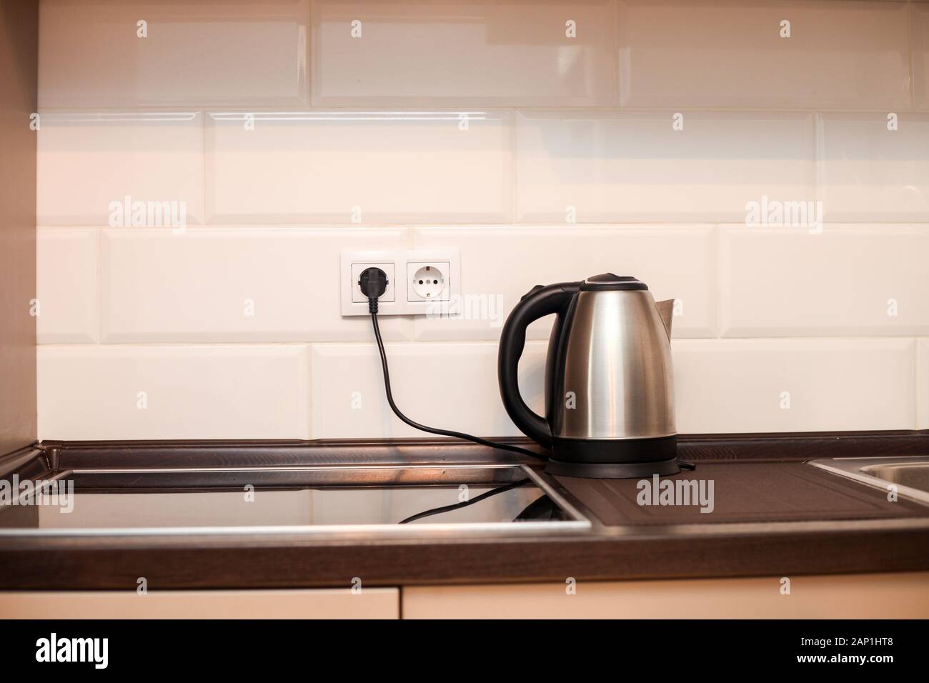 Modern kitchen with metal sink, kettle and white decorative wall