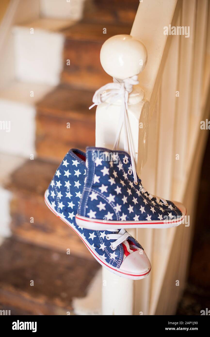 A pair of stars and stripes high-top shoes hanging on a banister Stock Photo